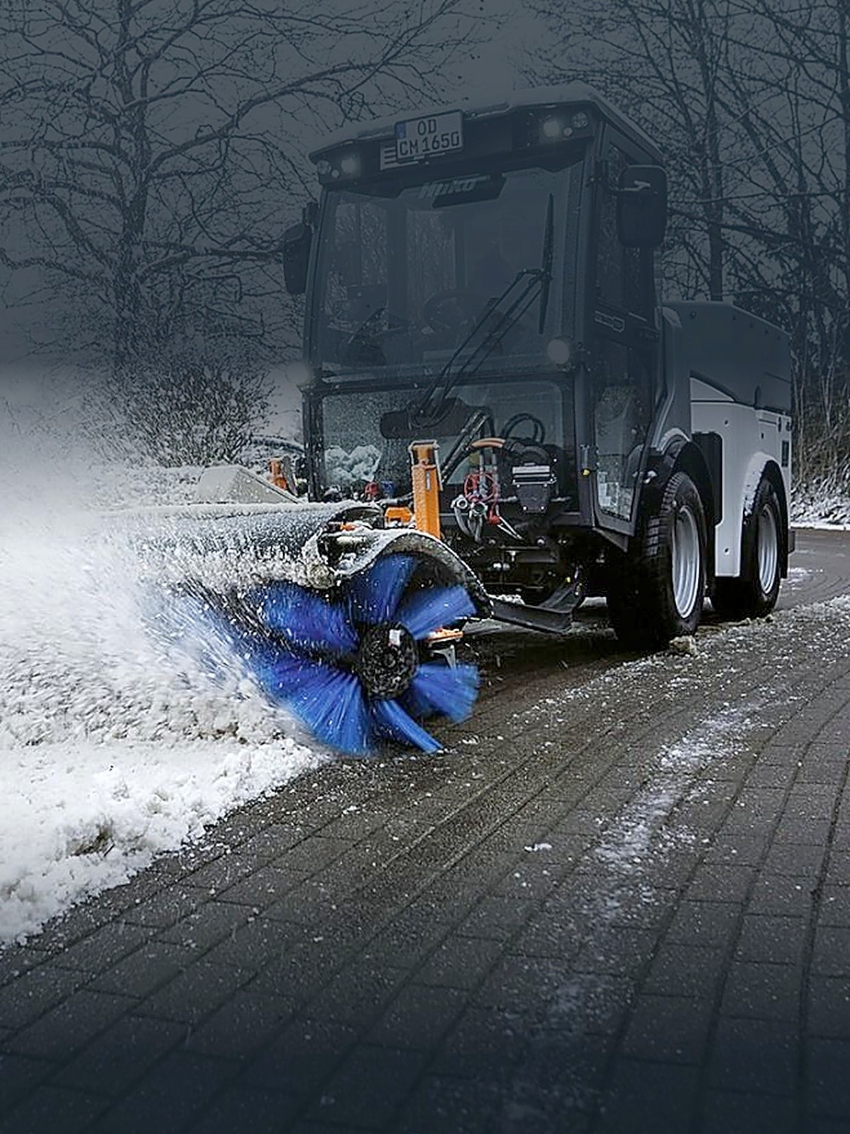 Kehrmaschine räumt Schnee von einem gepflasterten Weg