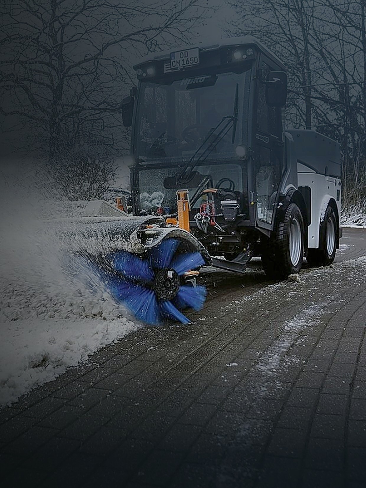 Kehrmaschine räumt Schnee von einem gepflasterten Weg